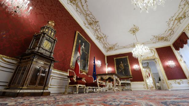 Ein prunkvoller Raum mit roter Tapete, goldenen Verzierungen und einem antiken Standuhr.