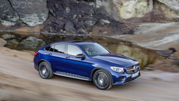 Ein blauer Mercedes-Benz GLC fährt auf einer unbefestigten Straße.