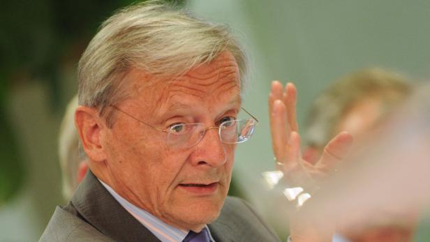 Ein älterer Mann mit Brille gestikuliert mit der Hand.