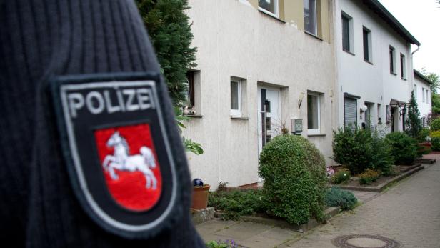 Das Abzeichen eines Polizisten vor einer Reihe von Reihenhäusern.