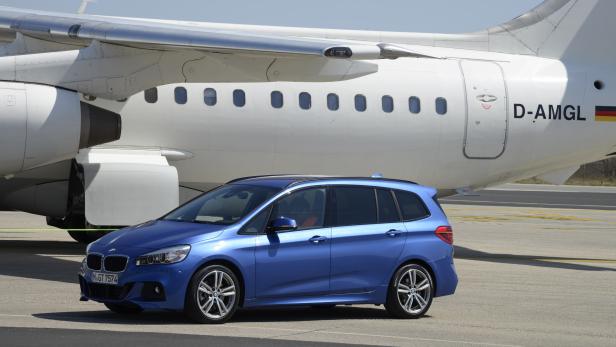 Ein blauer BMW 2er Active Tourer vor einem weißen Flugzeug.