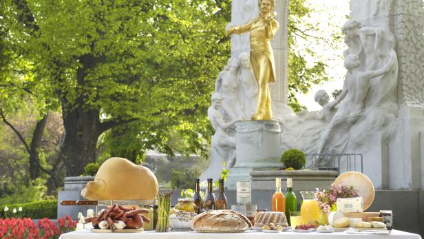 Ein Tisch mit Speisen vor dem Johann-Strauss-Denkmal in Wien.