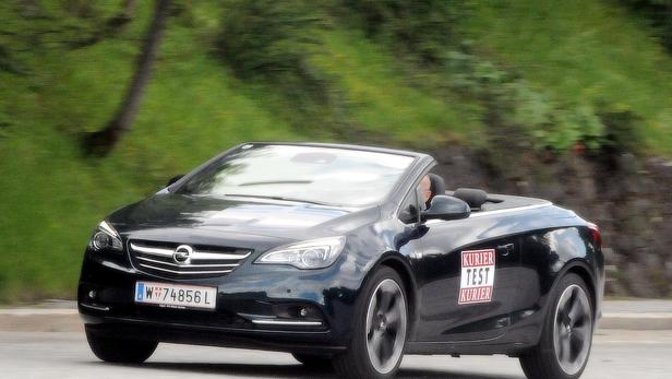 Ein schwarzer Opel Astra als Cabriolet fährt auf einer Straße.