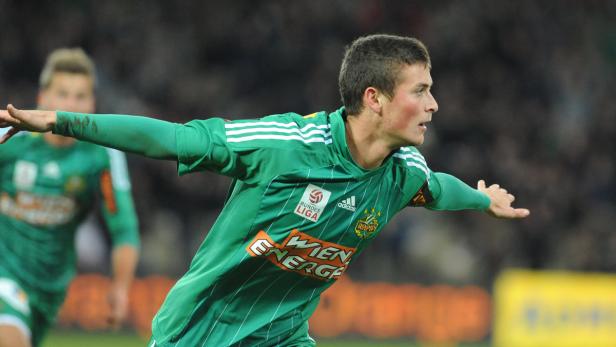 Ein Fußballspieler im grün-weißen Trikot streckt die Arme aus.