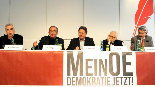 Fünf Männer sitzen an einem Tisch mit dem Aufdruck „MeinOE DEMOKRATIE JETZT!“.