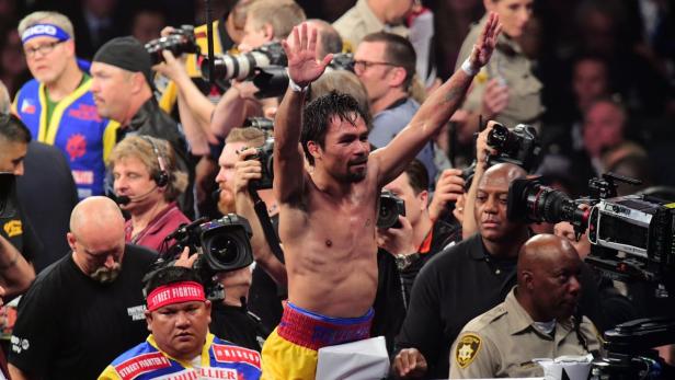 Manny Pacquiao feiert mit erhobenen Armen inmitten einer Menschenmenge.