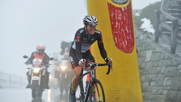 Ein Radfahrer fährt bei Regen an einem gelben Werbebanner vorbei.