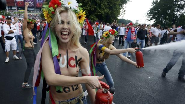 Frauen protestieren mit aufgemalten Parolen und Feuerlöschern auf der Straße.