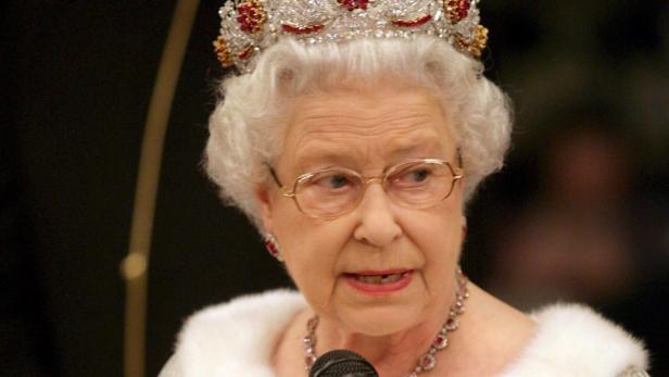 Königin Elisabeth II. mit Krone, Brille und Mikrofon bei einer Rede.