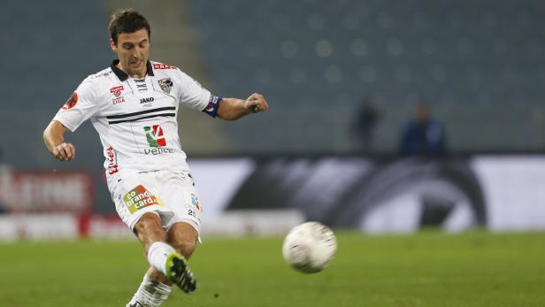 Ein Fußballspieler schießt den Ball auf dem Spielfeld.