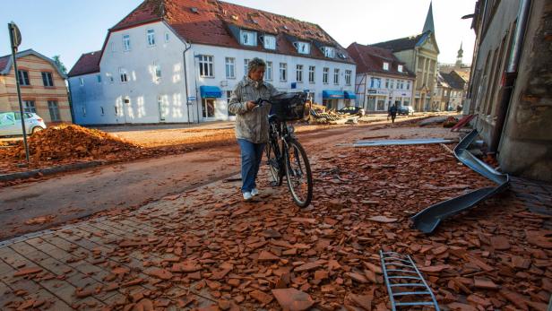 Eine Frau schiebt ihr Fahrrad durch eine Straße, die mit Ziegelsteinen übersät ist.