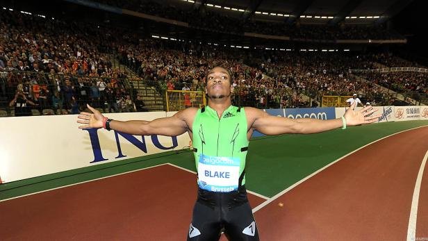 Yohan Blake feiert mit ausgebreiteten Armen auf einer Laufbahn vor Publikum.