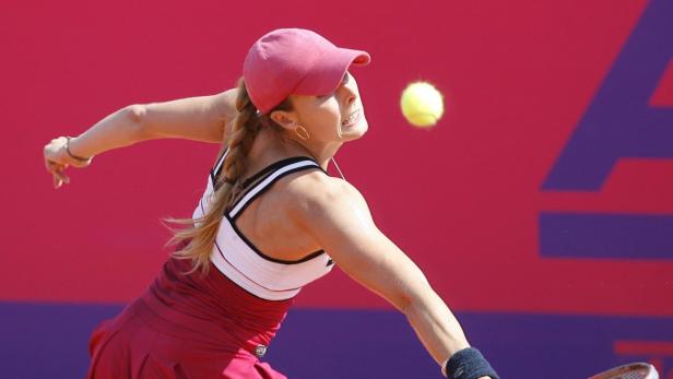 Eine Tennisspielerin schlägt einen gelben Tennisball vor einem roten Hintergrund.