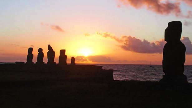 Silhouetten der Moai-Statuen auf der Osterinsel bei Sonnenuntergang.