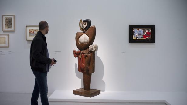 Ein Mann betrachtet eine abstrakte Holzskulptur in einer Kunstgalerie.