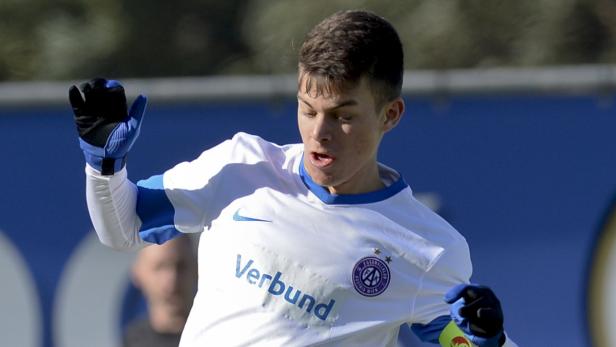 Ein junger Torwart in seinem Trikot mit Handschuhen auf dem Fußballplatz.
