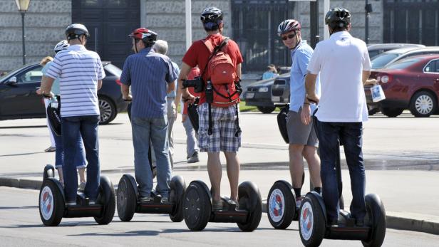 Eine Gruppe von Touristen fährt mit Segways durch eine Stadt.