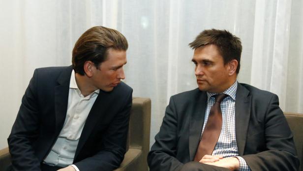 Zwei Männer in Anzügen sitzen nebeneinander und unterhalten sich.