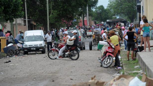 Eine belebte Straße mit Menschen, Motorrädern und einem Pferdekarren.