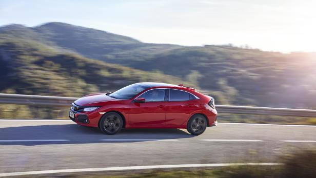 Ein roter Honda Civic fährt auf einer Landstraße entlang.