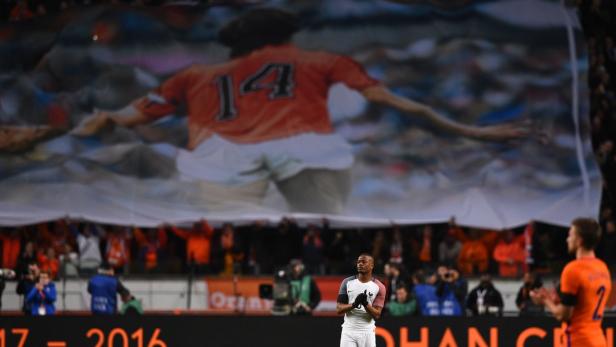 Ein Fußballspieler steht vor einem großen Banner mit der Nummer 14.