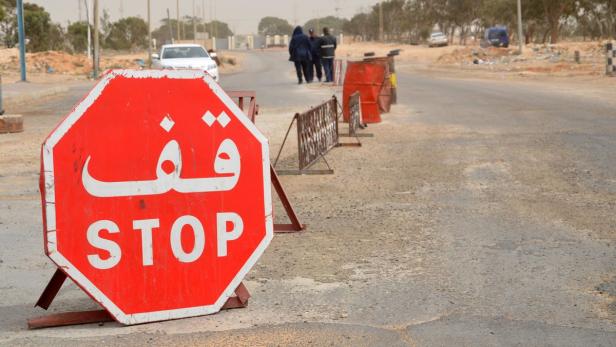 Ein Stoppschild mit arabischer und lateinischer Schrift steht an einer Straße.