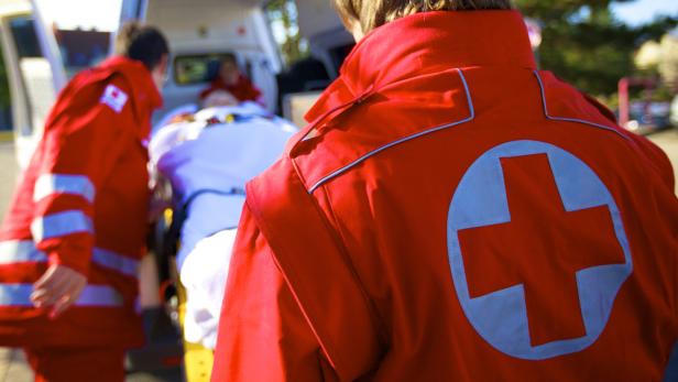 Sanitäter schieben eine Person auf einer Trage in einen Krankenwagen.