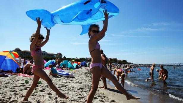 Mirabelle und Patricia aus Niedersachsen tragen am Strand von Kühlungsborn einen aufblasbaren Delfin in die Ostsee.