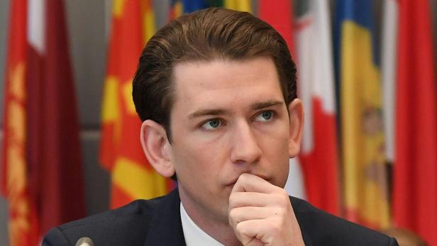 Sebastian Kurz bei einer Veranstaltung mit verschiedenen Nationalflaggen im Hintergrund.