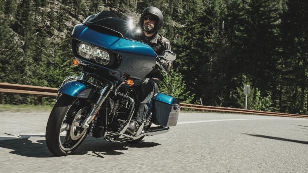 Ein Mann fährt mit einem blauen Motorrad auf einer kurvigen Straße.