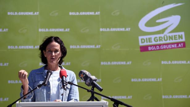 Eine Frau spricht vor einem Hintergrund mit dem Logo der Grünen Burgenland.