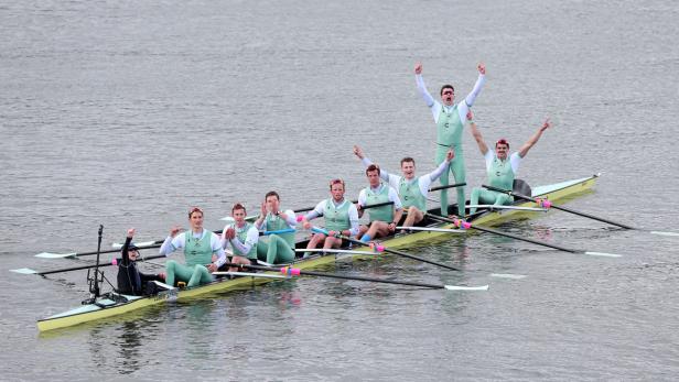Ein Ruderteam jubelt in einem Rennboot auf dem Wasser.