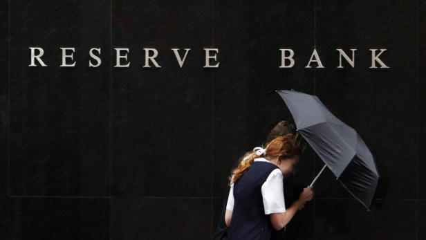 People walk past the Reserve Bank of Australia (RBA) building during rainy weather in central Sydney in this December 1, 2009 file photo. Australia faces a gathering threat to its 21-year run of recession-free growth that will likely require the central bank to cut interest rates to record lows and keep them there for some time, if the winning streak is to stretch to 22. To match Analysis AUSTRALIA ECONOMY/BOOM REUTERS/Daniel Munoz/Files (AUSTRALIA - Tags: POLITICS BUSINESS)