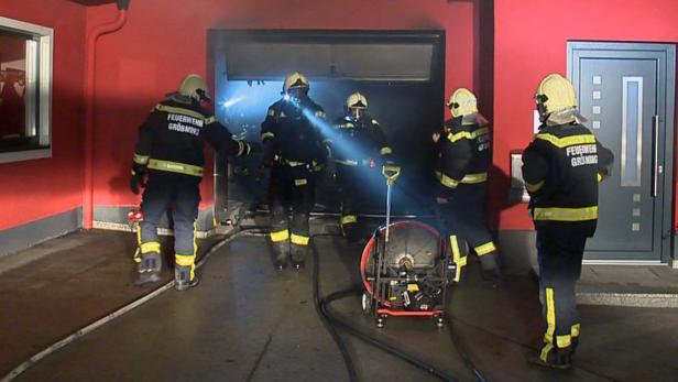 Mehrere Feuerwehrleute stehen vor einem Gebäude, möglicherweise während eines Einsatzes.