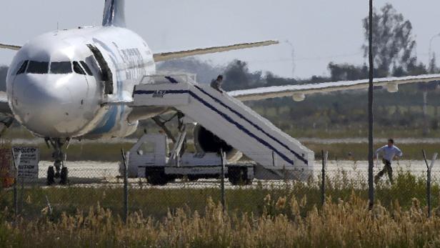 Unidentified people run off the hijacked Egyptair Airbus A320 at Larnaca Airport in Larnaca, Cyprus, March 29, 2016 REUTERS/Yiannis Kourtoglou