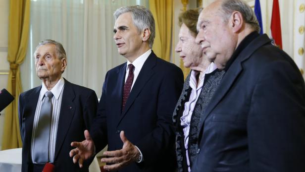 Eine Gruppe von vier Personen steht in einem formellen Rahmen.