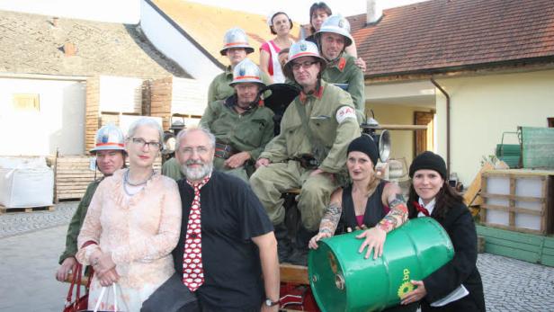 Eine Gruppe von Personen posiert auf einem alten Feuerwehrfahrzeug.