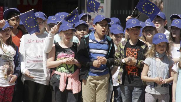 Eine Gruppe Kinder mit EU-Fahnen und -Mützen demonstriert vermutlich für Europa.