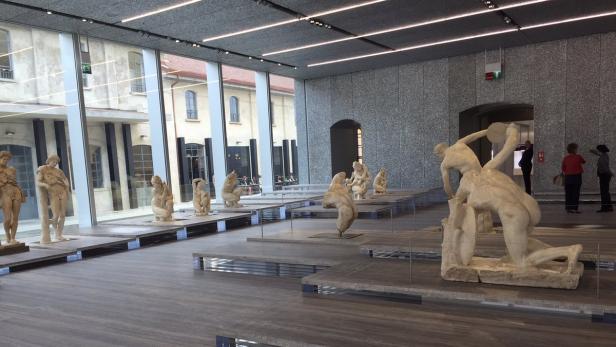 Innenansicht eines Museums mit einer Sammlung von Skulpturen auf Sockeln.