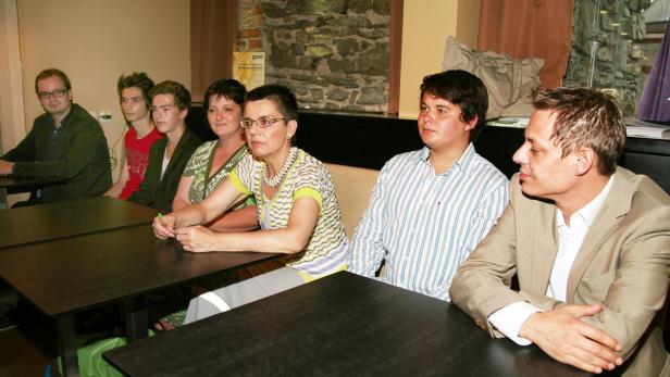 Eine Gruppe von Personen sitzt an Tischen in einem Raum.