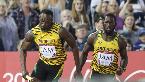 Usain Bolt übergibt den Staffelstab während eines Rennens an seinen Teamkollegen.