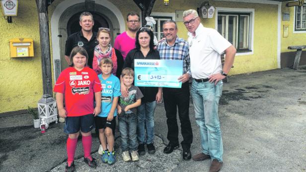 Eine Gruppe von Menschen posiert mit einem Scheck der Sparkasse über 3482 Euro.
