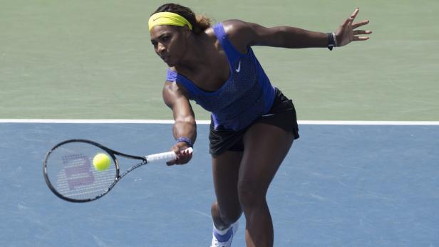 Serena Williams schlägt einen Tennisball auf einem blauen Platz.