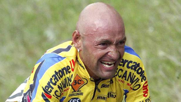 Ein Radrennfahrer in gelbem Trikot mit schmerzverzerrtem Gesichtsausdruck.