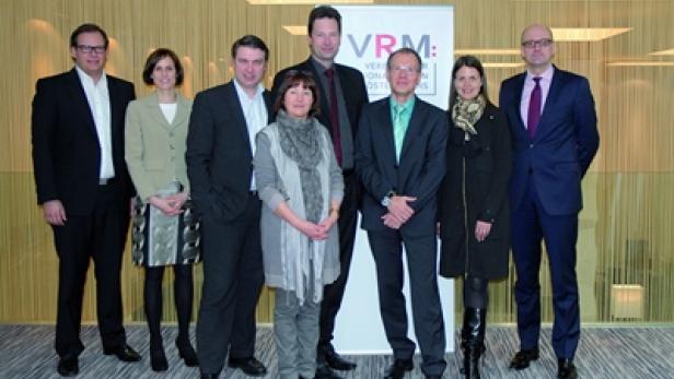 Eine Gruppe von acht Personen posiert vor einem VRM-Banner.