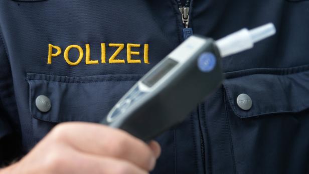 Ein Polizist hält ein Alkoholtestgerät in der Hand.