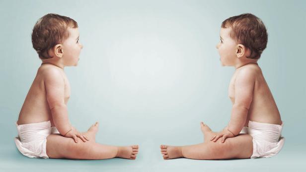 Zwei Babys sitzen sich gegenüber und scheinen miteinander zu sprechen.
