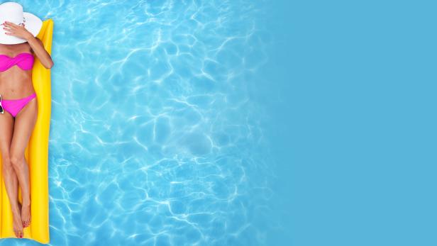 Eine Frau mit Hut und Bikini entspannt auf einer gelben Luftmatratze im Wasser.