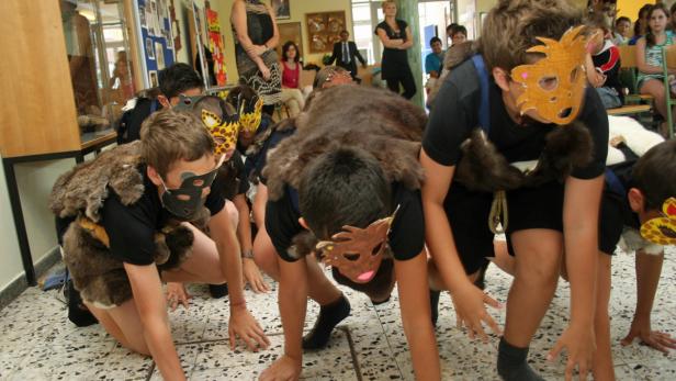 Eine Gruppe Kinder in Tierkostümen und Masken spielt in einem Raum.