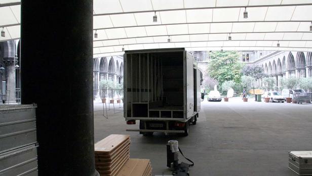 Ein Lieferwagen steht in einem Innenhof mit Arkaden und vorbereitetem Equipment.